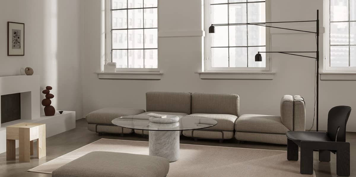 Neben einem Sofa mit Couchtisch steht eine grosse Stehleuchte, deren zwei Leucht-Arme individuell bewegt werden k&ouml;nnen